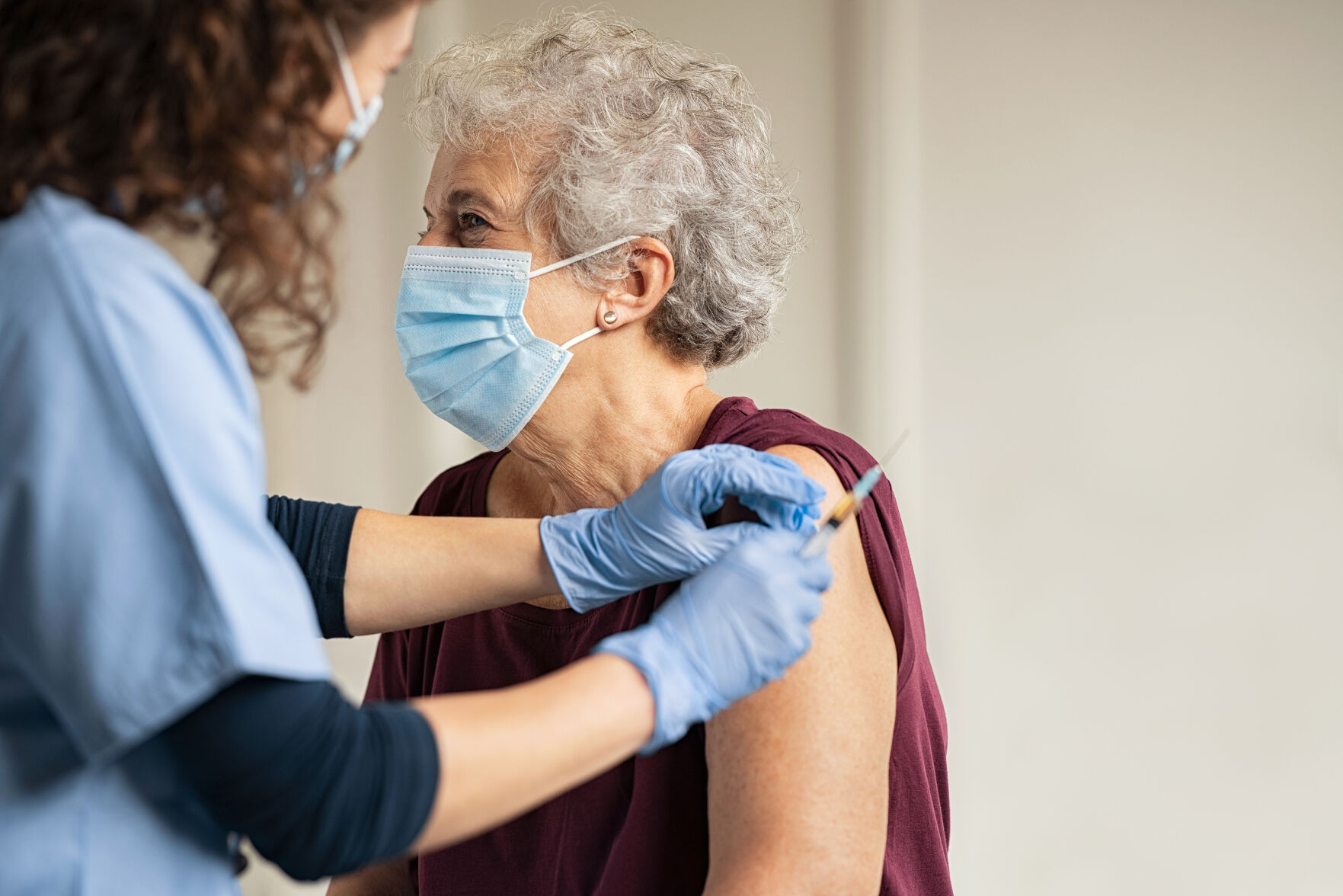General practitioner vaccinating old patient in clinic with copy space. Doctor giving injection to s